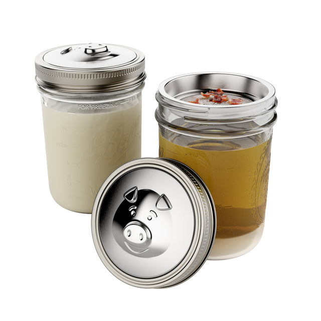 Jarware Mason Jar Stainless Steel Grease Keepers, on two different wide mouth Mason jars; one with solidified grease, one with still warm grease and little bits of bacon in the strainer.