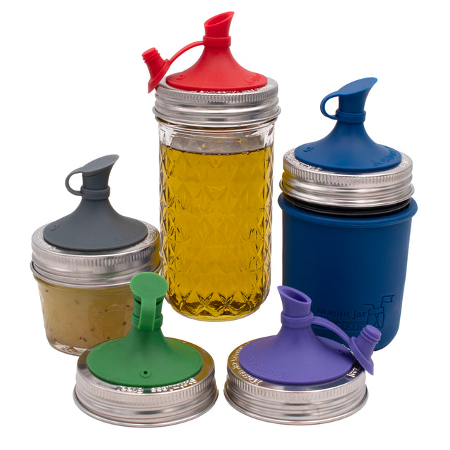 Silicone oil cruet lids with stainless steel bands in five colors, shown on three Mason jars and as two separate lids.