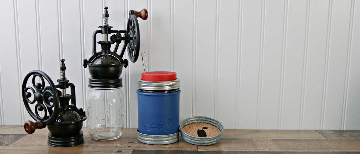regular mouth vintage reproduction coffee grinders with deep blue wide mouth silicone pint sleeve, wide mouth cherry red silicone straw hole lid, and wide mouth galvanized lid cork coaster