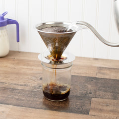 Hot water being poured into a stainless steel pour-over coffee filter on a Mason jar.